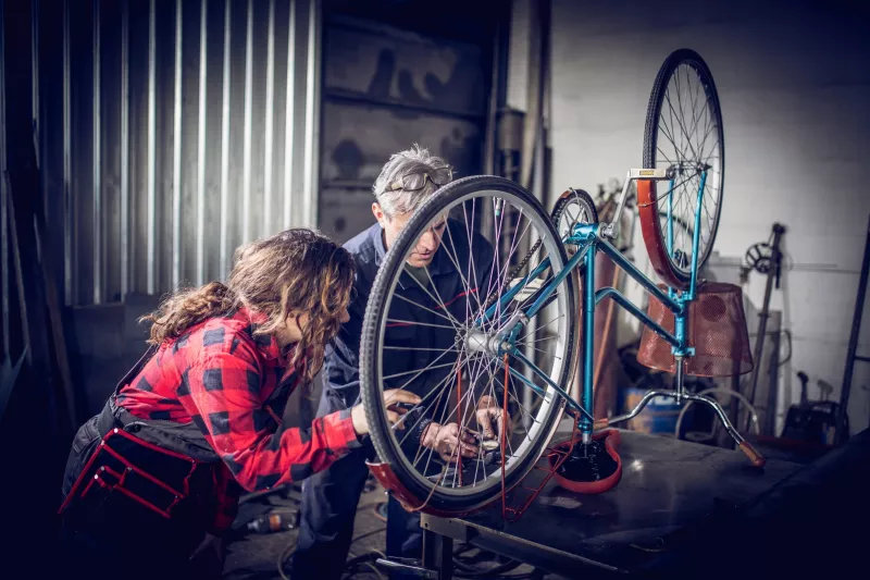 Two people fixing a bike together in the garage.